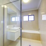 White Elegant Bathroom With Glass Shower Door Big Mirror And White Tub
