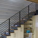 elegant understairs home office design with creamy storage with white chair and wall racks and black stairs railing and wooden siding