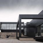 gothic black eco friendly modern house deisgn with glass siding and black roof and wall and outdoor living space