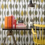 playful retro wallpaper design with leave shape and black glossy desk and yellow chair and orange case and black table lamp