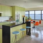 spacious kitchen studio design with yellowish storage idea with soft blue stools and glossy flooring with orange dining table with glass window
