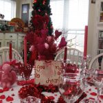 gorgeous red christmas centerpiece design with rose and red candles and ribbon and navity
