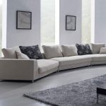 gorgeous white interior design with long white sectional sofa design and black patterned cushion and glass window and wall picture