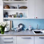 gorgeous white kitchen design with blue small tile mosaic backsplash and white upper cabinet and indoor plant