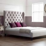 luxury scarlett tall upholstered bed with luxurious tufted headboard and wooden floor plus nightstand table and round mirror on wall