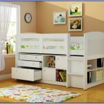 White toddler sized bed frame with side rail headboard footboard under bookshelves and drawer system cute bedroom rug for kids