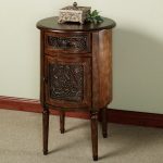 tall wood accent table with round tabletop and handcrafted decoration on storage door