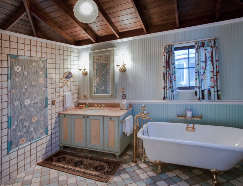 small eclectic bathroom in traditional style freestanding bathtub in white with gold toned shower fixtures blue finish bathroom vanity with cream top undermount sink terracotta tiles floors and side w