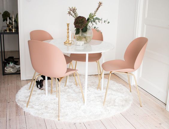 soft pink chairs with brass legs round marble top dining table round white shag rug wood board floors