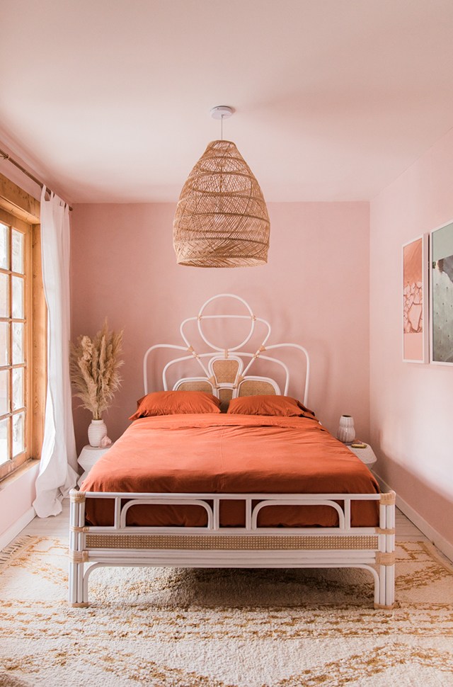 soft pink walls warm orange bed linen and pillowcovers classic bed frame with curly headboard soft tone shag rug extra large pendant with fish trap lampshade