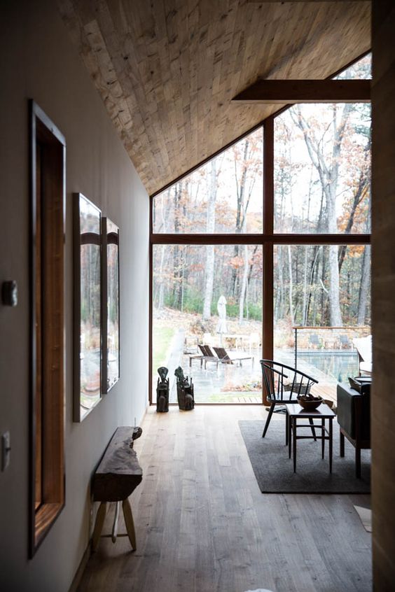 modern cabin's interior with fully glass windows with wood trims and slanted wood ceilings
