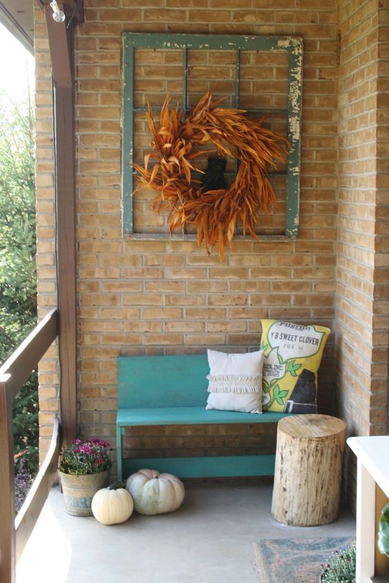 small bench seat with back in blue log side table red brick walls ex window trim wall decor with dried leave wreath in the center