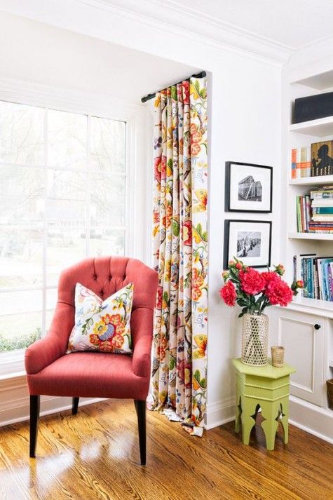 coral armchair with a throw pillow multicolored window curtains green side table