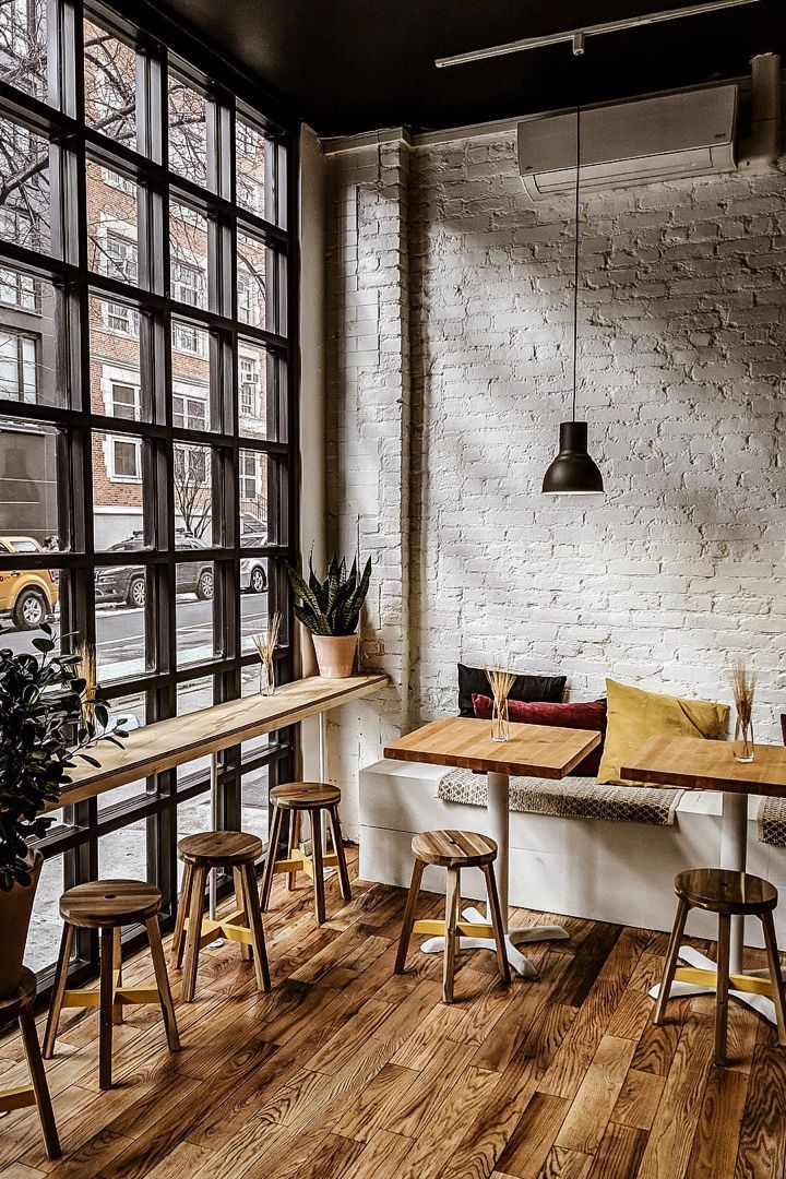 coffee shop interior with white brick walls industrial style window floating wooden bench table natural wood stools small wood tables white bench seat wooden floors
